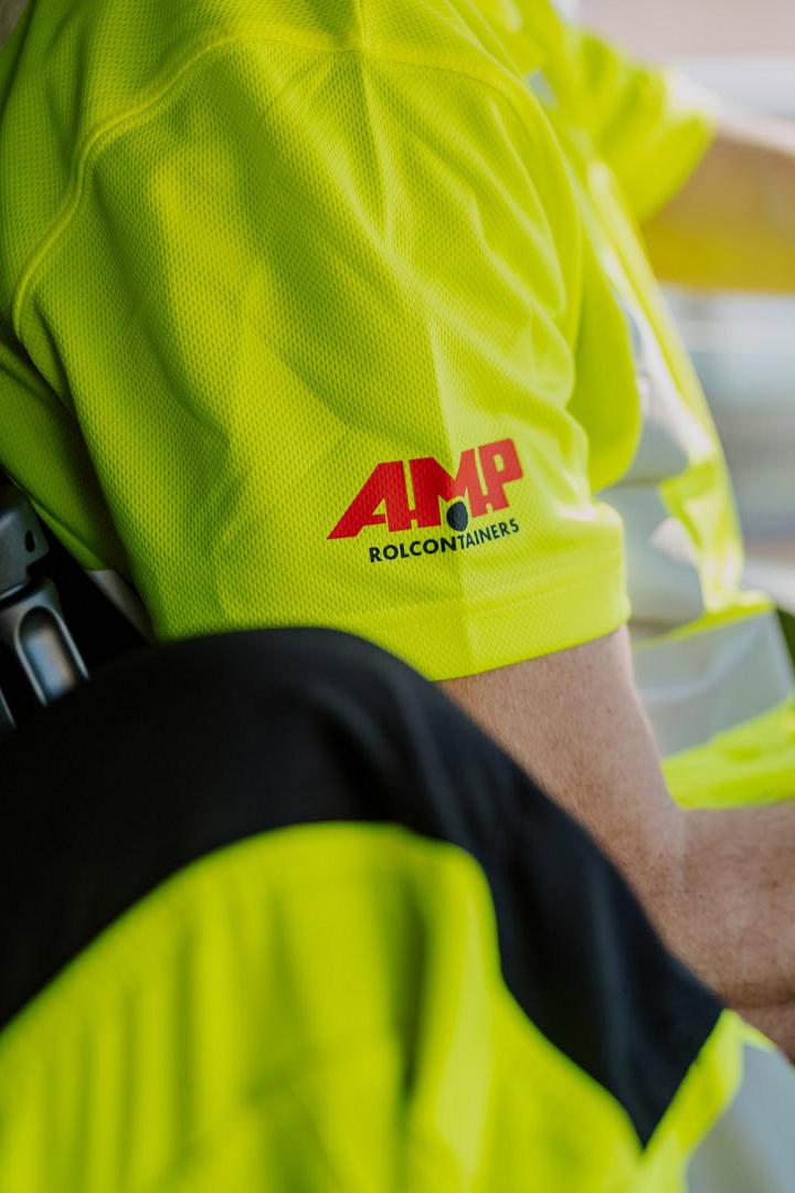 Close-up van een AMP-medewerker in fluorescerend uniform achter het stuur van een vrachtwagen.