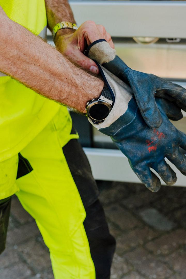 Close-up van een AMP-medewerker die veiligheidshandschoenen aantrekt voor het werk.