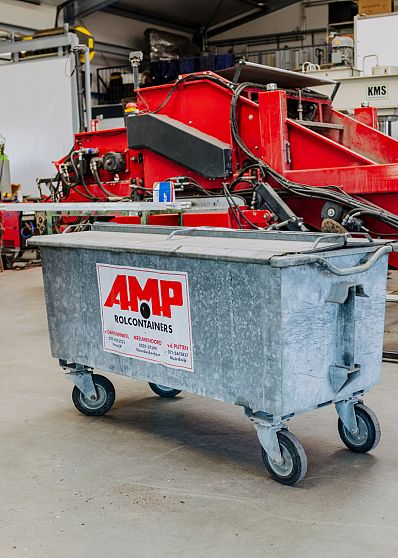 Metalen rolcontainer van AMP Rolcontainers in een werkplaats met rode machines.