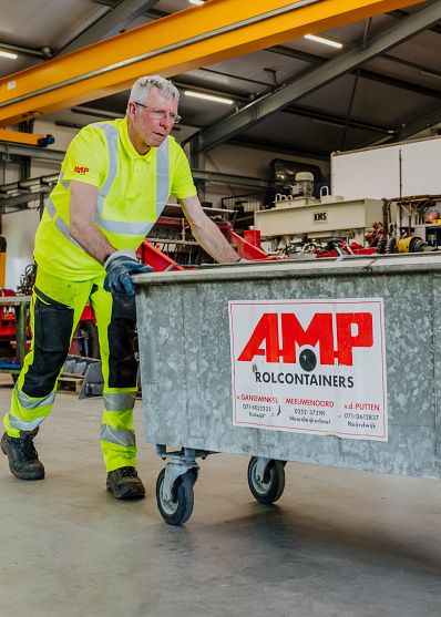 AMP-medewerker rolt ijzeren container voor zich uit in een loods.