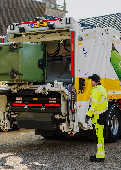 Twee mannen in geel pak bij vuilniswagen legen container.