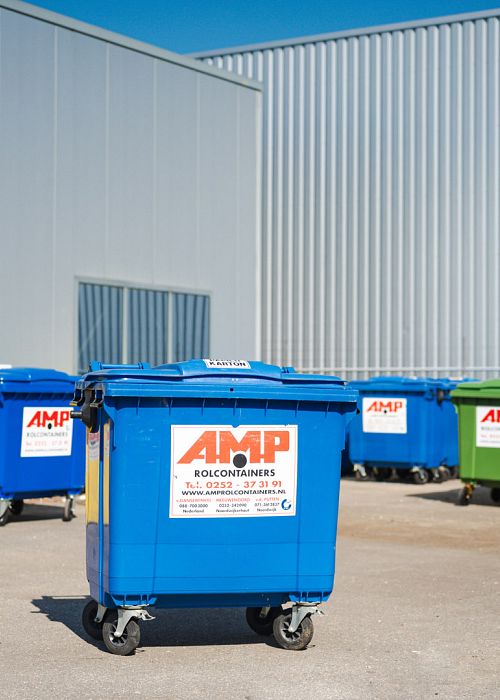 Blauwe AMP-container op terrein met meerdere gekleurde rolcontainers bij industriepand.