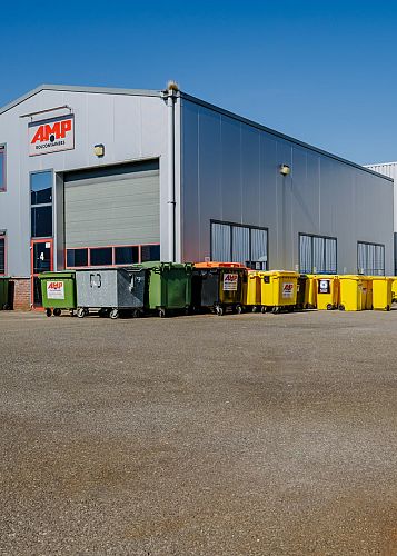 Bedrijfshal van AMP Rolcontainers met meerdere afvalcontainers op het terrein.
